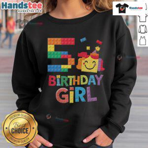 5th birthday girl in a colorful sweatshirt, building with brick blocks, celebrating her special day with creativity.