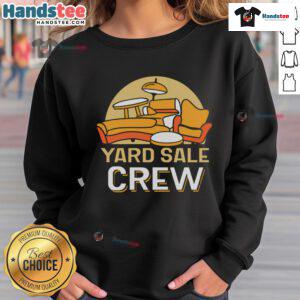 Good yard sale crew seller showcasing cozy sweatshirts at a vibrant outdoor market.