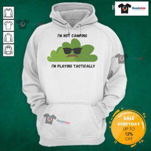 Funny 'I'm Not Camping, I'm Playing Tactically' hoodie in a bush setting, perfect for outdoor enthusiasts and humor lovers.