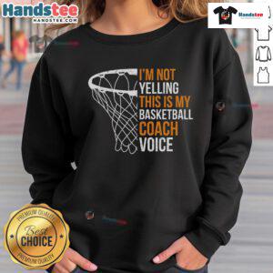 Basketball coach wearing a 'This is my basketball coach voice' sweatshirt, smiling and engaging with players on the court.