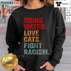 Distressed typography sweatshirt featuring 'Drink Water, Love Cats, Fight Racism' message in bold colors.