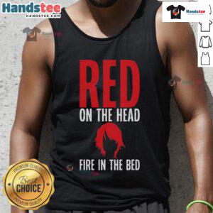 Funny redhead wearing a tank top with a fire graphic on the bed, showcasing a playful and vibrant personality.