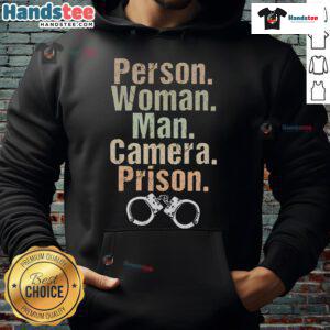 Funny woman and man in hoodies posing with a camera in a playful prison setting, capturing a lighthearted moment.
