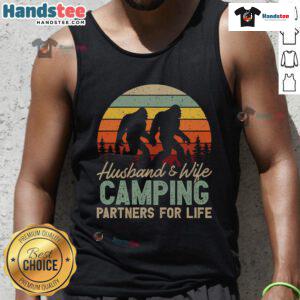 Happy husband and wife wearing 'Good Bigfoot Camping Partners for Life' tank tops, enjoying a cozy outdoor moment.