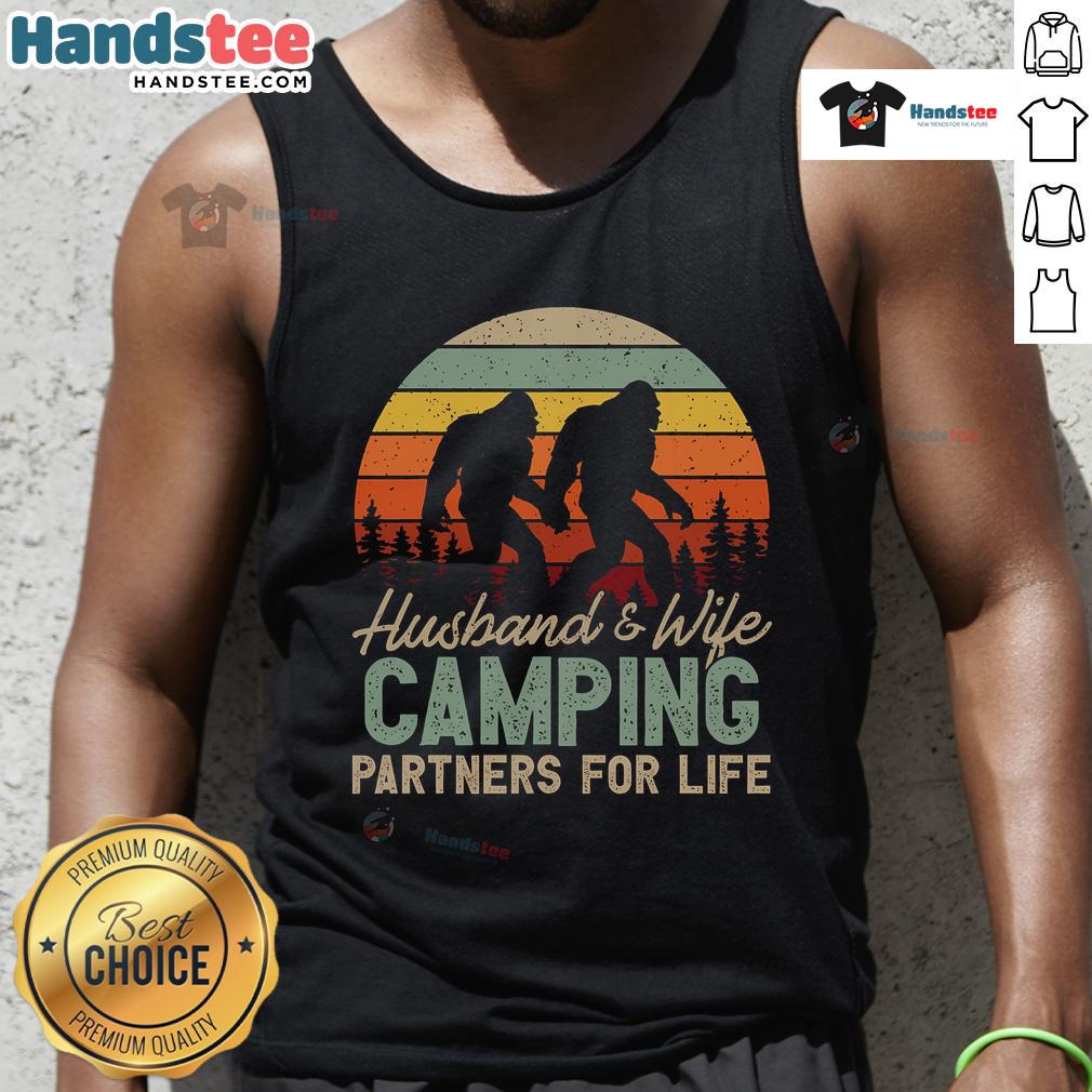 Happy husband and wife wearing 'Good Bigfoot Camping Partners for Life' tank tops, enjoying a cozy outdoor moment.
