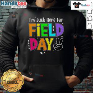 Teacher wearing a 'Good I'm Just Here For Field Day' hoodie, smiling outdoors during a school field day event.