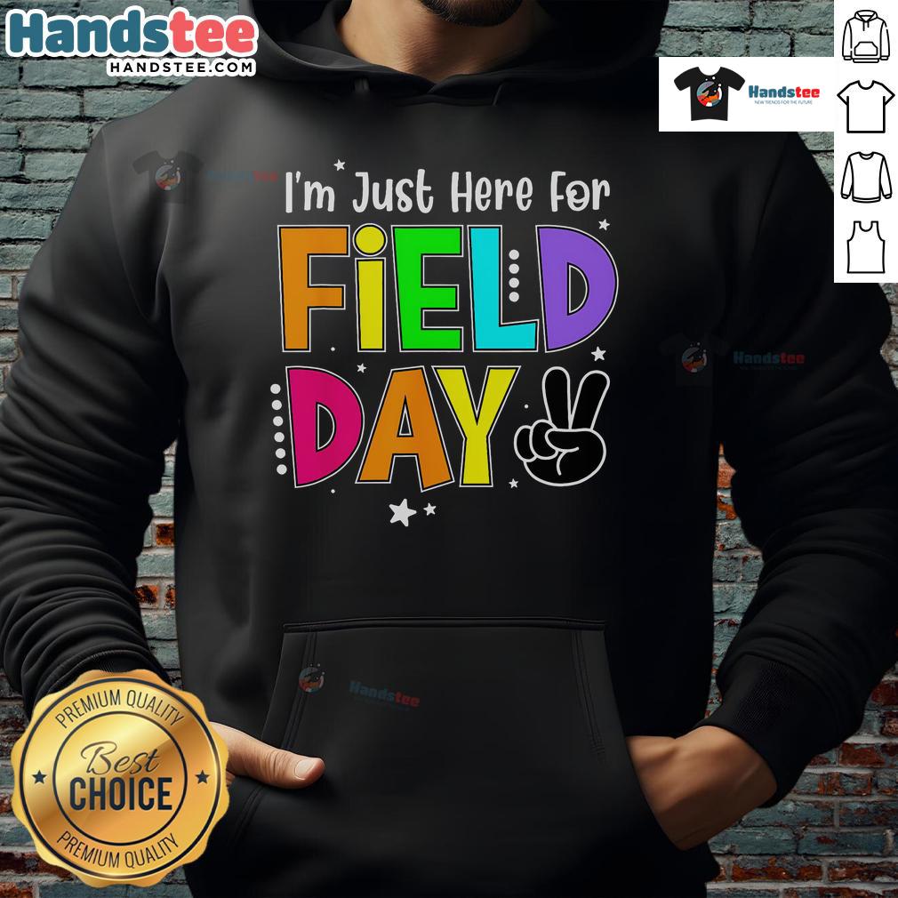 Teacher wearing a 'Good I'm Just Here For Field Day' hoodie, smiling outdoors during a school field day event.