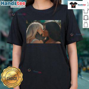 Sabrina Carpenter and Jenna Ortega share a kiss in a stylish 'Kiss and Murder' ladies tee, showcasing their vibrant fashion.