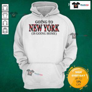 Cozy Happy Going to New York is Going Home hoodie worn by a smiling person in a vibrant cityscape background.