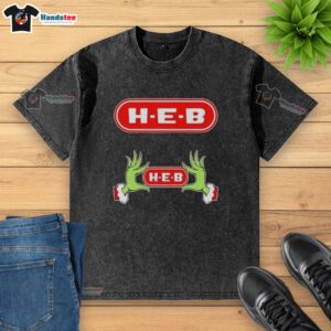 Festive Grinch hands holding a heart on an H-E-B Christmas washed t-shirt, perfect for holiday cheer and seasonal style.
