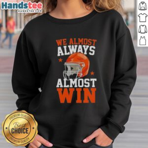 Happy football fan wearing 'We Almost Always Almost Win' sweatshirt, showcasing team spirit and humor at the game.