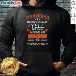 Cheerful grandma in Chicago Bears hoodie, passionately reacting while watching a football game, showcasing her team spirit.