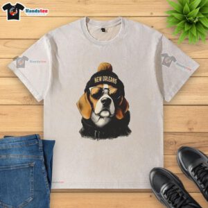 Alt Text: New Orleans Saints mascot in a beanie and sunglasses, showcasing a washed t-shirt at a lively game event.