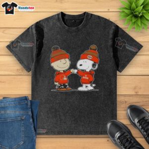 Charlie Brown and Snoopy fist bump in Cleveland Browns football t-shirt, showcasing playful Peanuts fandom.