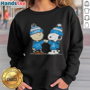 Charlie Brown and Snoopy fist bump on a Detroit Lions football sweatshirt, perfect for Peanuts fans and sports lovers.