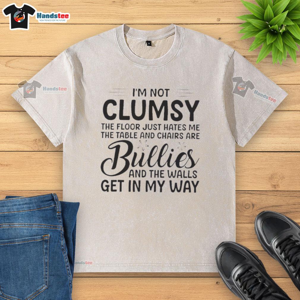 Alt Text: Premium I'm Not Clumsy, The Floor Just Hates Me washed t-shirt displayed on a wooden table with chairs.