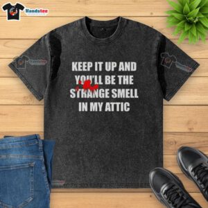 Funny 'Nice Keep It Up And Youll Be The Strange Smell In My Attic' washed t-shirt displayed on a wooden background.
