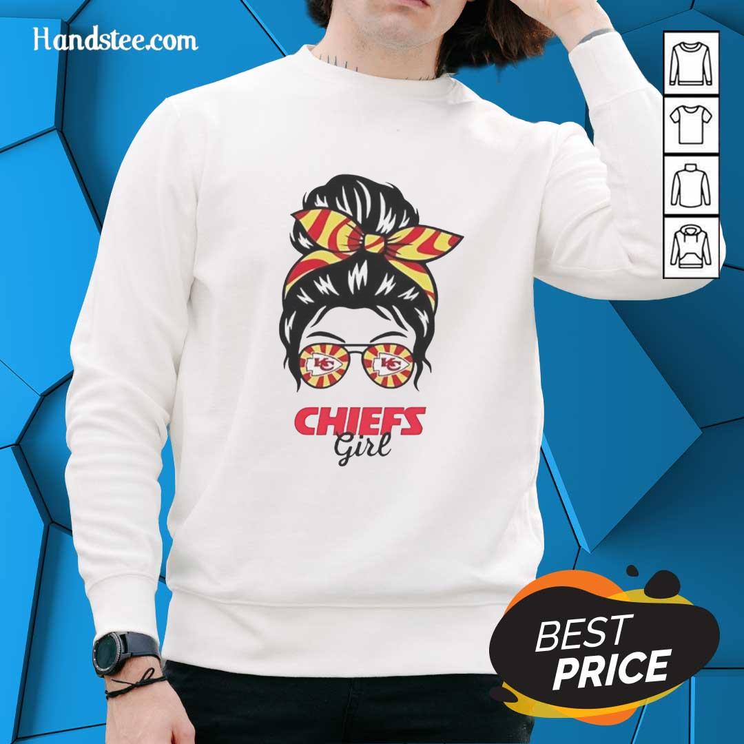 Cheerful Kansas City Chiefs girl in a messy bun, wearing glasses and a stylish sweatshirt, showing team spirit.