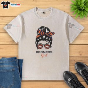 Alt Text: Official Denver Broncos girl wearing messy bun and glasses, showcasing a stylish washed t-shirt in team colors.