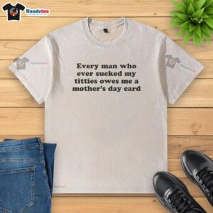 Washed t-shirt with 'Every man who ever sucked my titties owes me a Mother's Day card' graphic for humorous fashion.