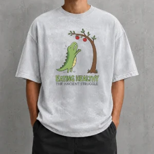 Funny T Rex Eating Healthy The Ancient Struggle design on a soft washed t shirt in light gray